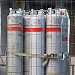 Tall metal gas canisters secured in wired cage